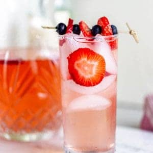 A large glass of strawberry sangria with fresh strawberry slices.