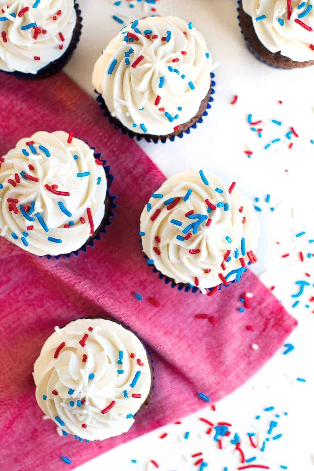 Overhead view of chocolate cupcakes with vanilla buttercream and red, white, and blue sprinkles.