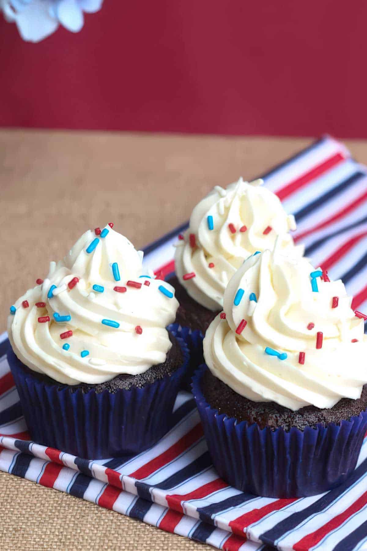 Chocolate cupcakes with vanilla buttercream frosting served on a tray with a red, white, and blue napkin.