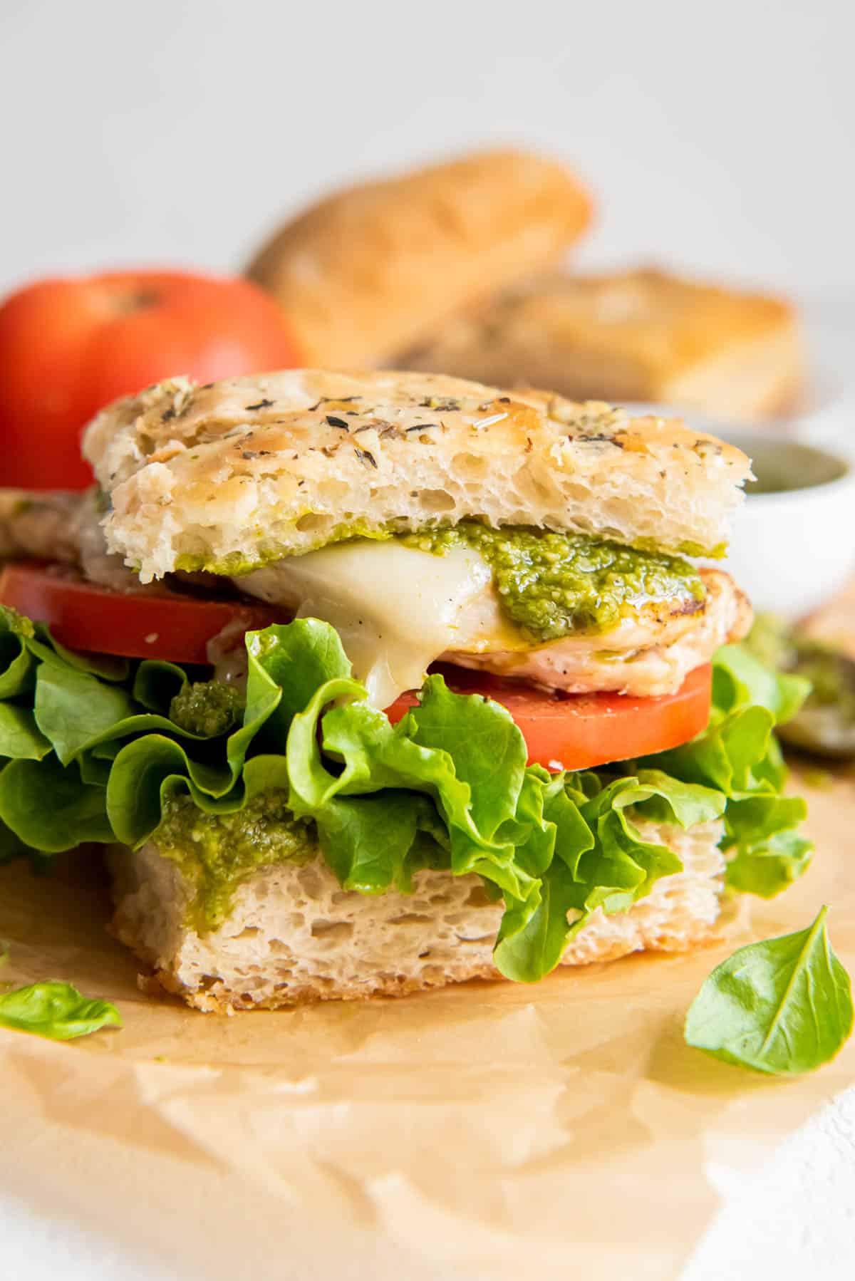 bread stacked with lettuce, tomato, grilled chicken, mozzarella cheese and pesto to create a sandwich.