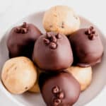 a bowl of cookie dough truffles sitting on a white countertop