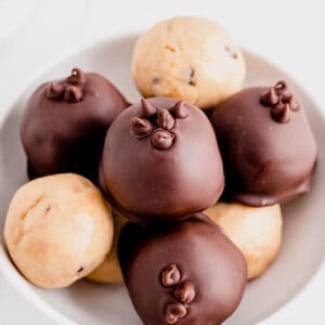 a bowl of cookie dough truffles sitting on a white countertop