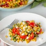 sautéed corn with tomatoes, basil and feta cheese on a plate