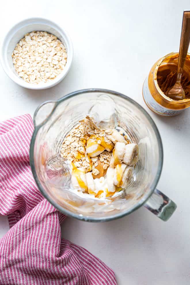 Peanut butter, banana, oats and more in a blender to make peanut butter banana smoothie.