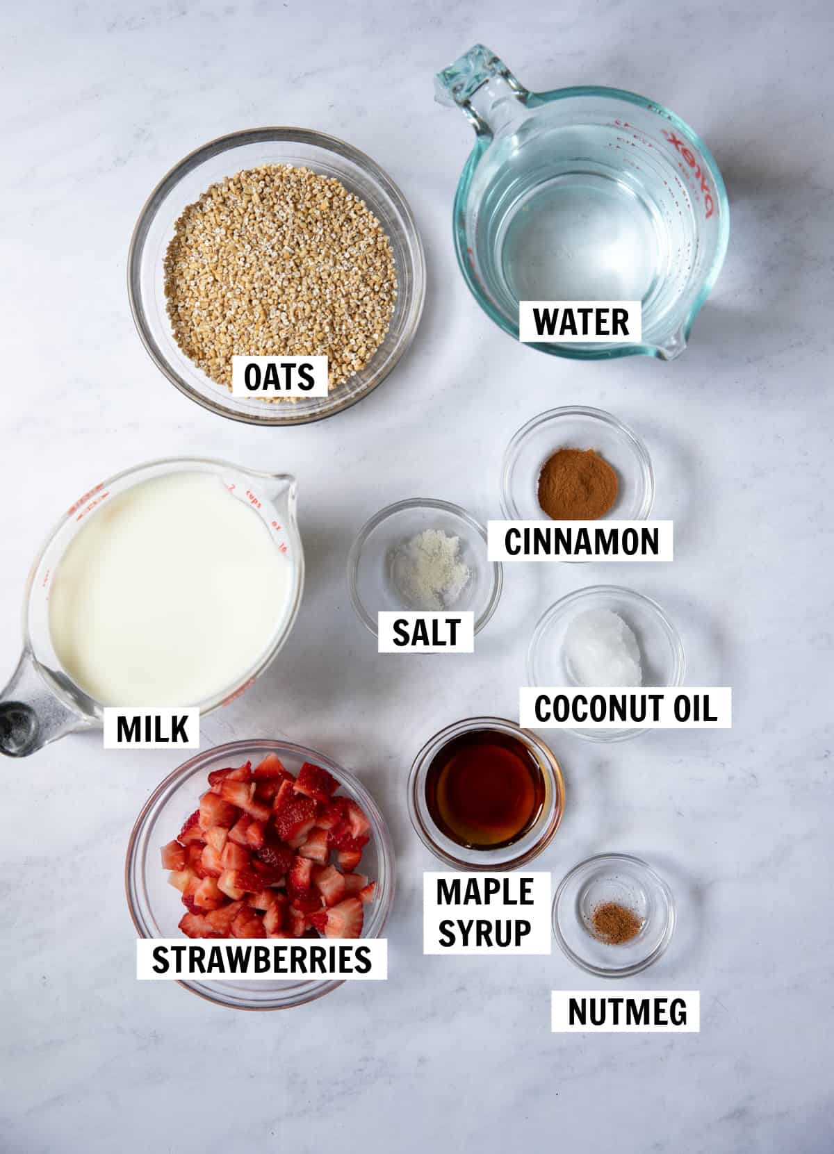 all of the ingredients for strawberry oatmeal on a white tabletop.