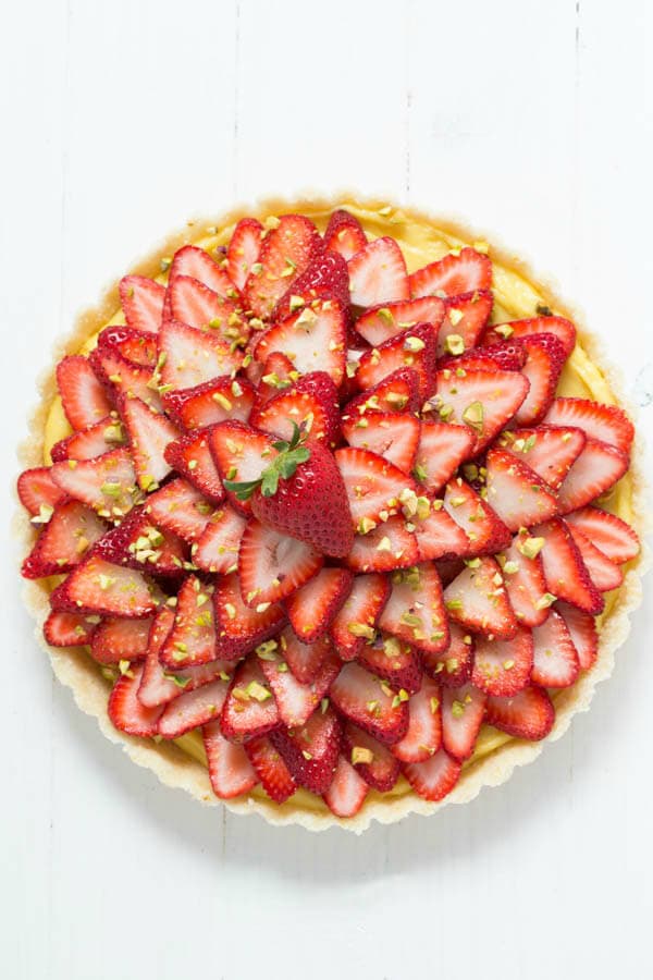 Strawberry Pistachio Cardamom Tart is made with a lemon coconut crust, cardamom pastry cream, fresh strawberries and pistachios! It is gluten free and dairy free too!