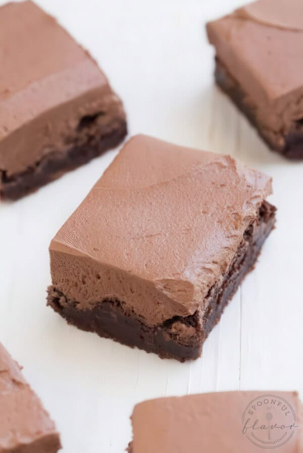 A brownie with chocolate frosting sitting on a white countertop.