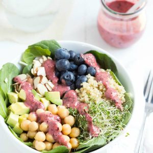 Spring Superfood Bowl with Blueberry-Ginger Dressing - a bed of fresh greens is topped with blueberries, quinoa, sprouts, chickpeas, avocado, almonds and blueberry-ginger dressing!