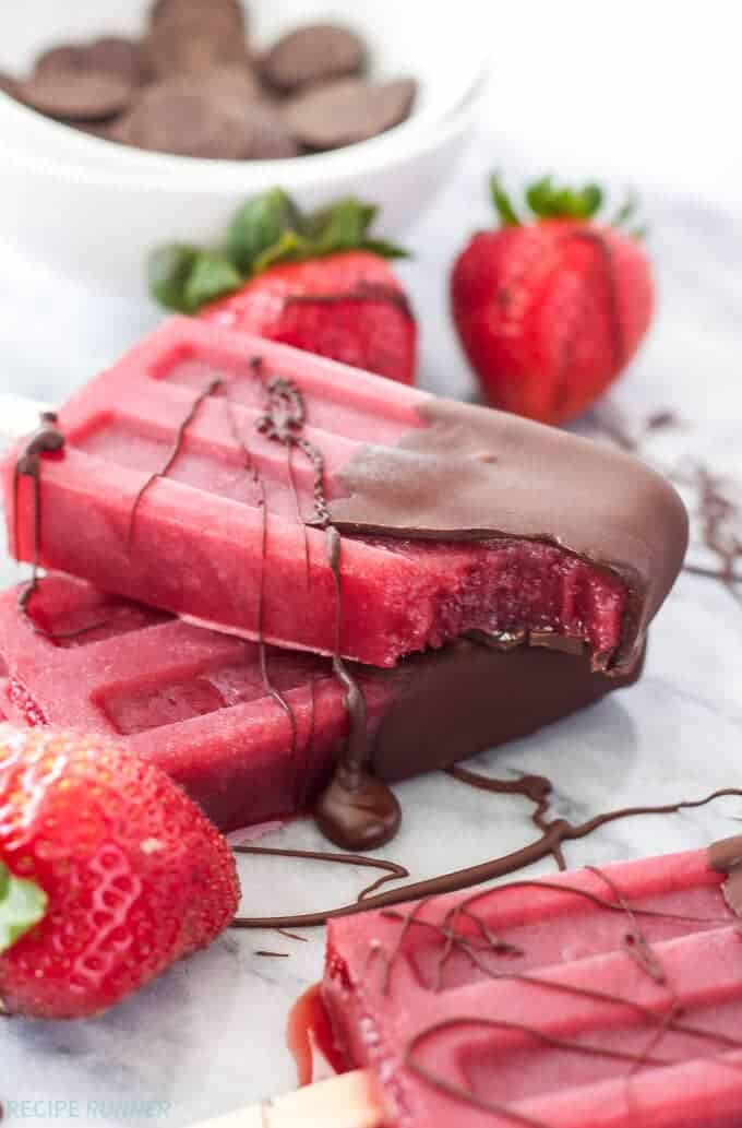Strawberry red wine popsicles with chocolate sauce on them.
