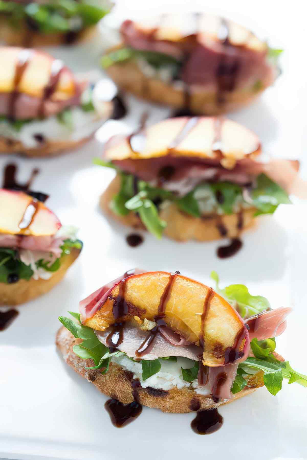 Grilled peach crostini topped with goat cheese, arugula, prosciutto and balsamic reduction.