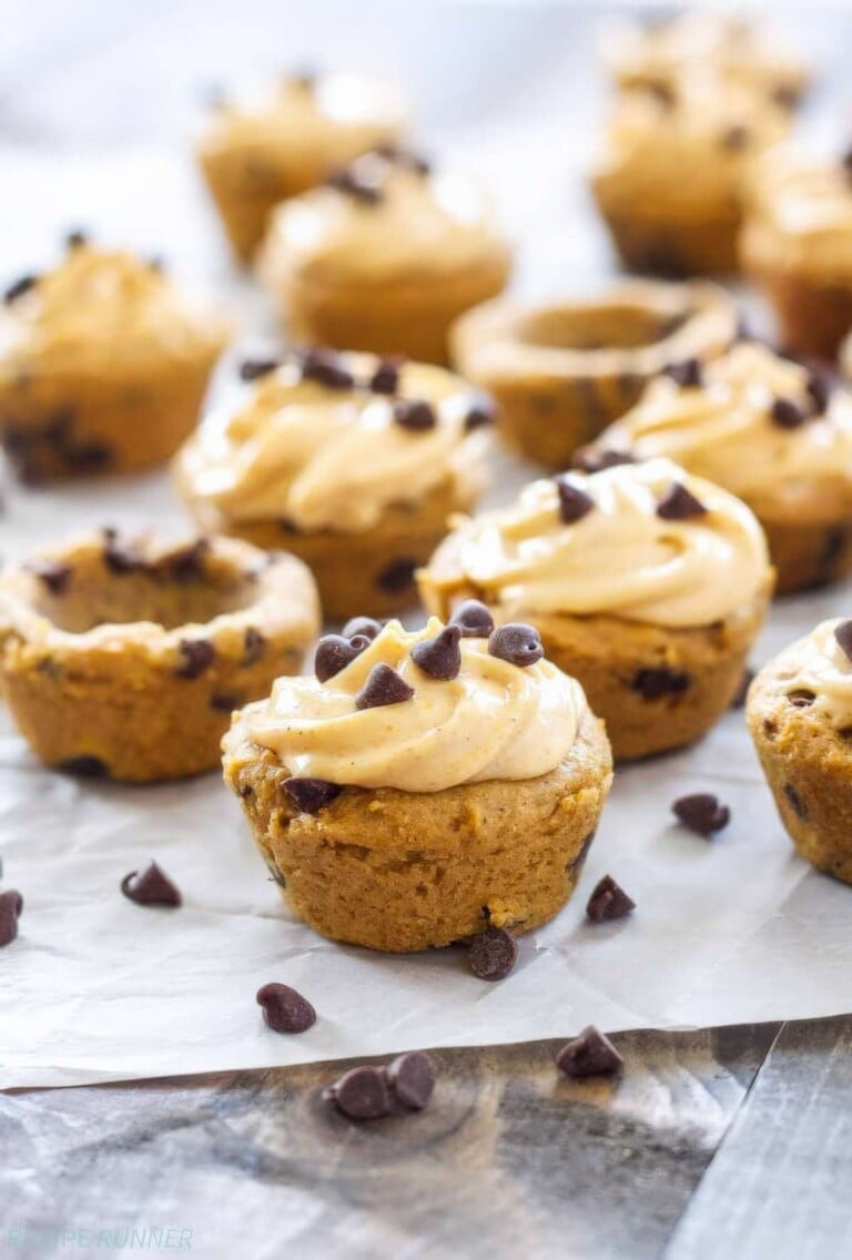 Mini pumpkin chocolate chip cookie cups filled with swirls of pumpkin cream cheese frosting and topped with extra chocolate chips.