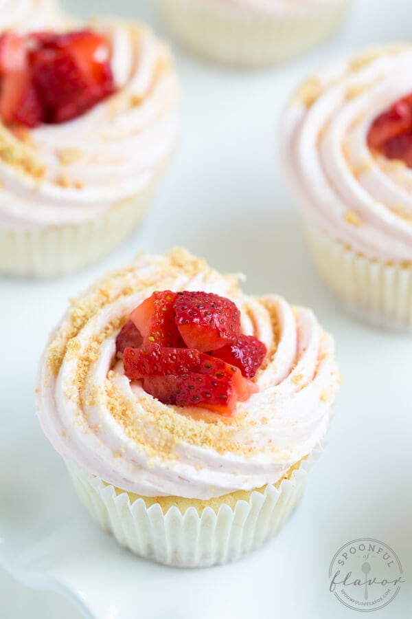 Strawberry Cheesecake Cupcakes are a delectable dessert made with vanilla cupcakes stuffed with cream cheese filling and topped with strawberry buttercream and fresh berries!