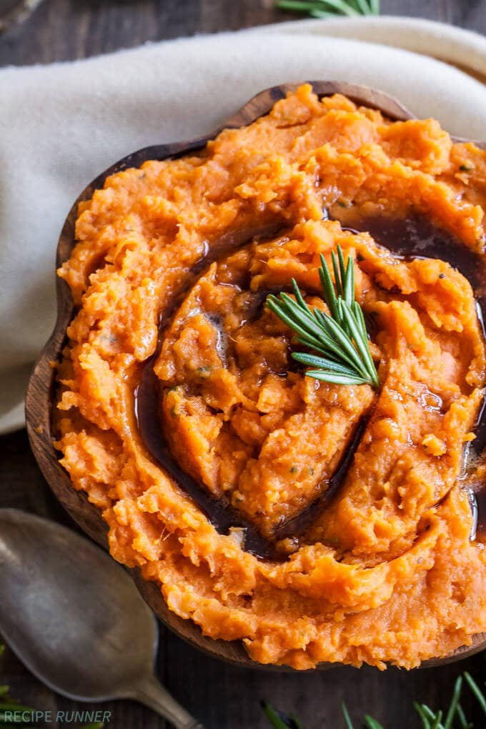 savory mashed sweet potatoes in a bowl with a rosemary spring on top 