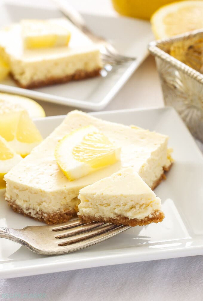 A fork on a white plate with a slice of lemon cheesecake bar