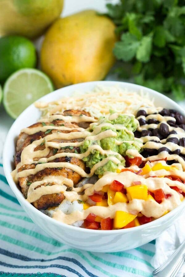 Chicken taco bowl with chipotle lime chicken, rice, black beans, mango salsa, guacamole, and creamy mango chipotle sauce
