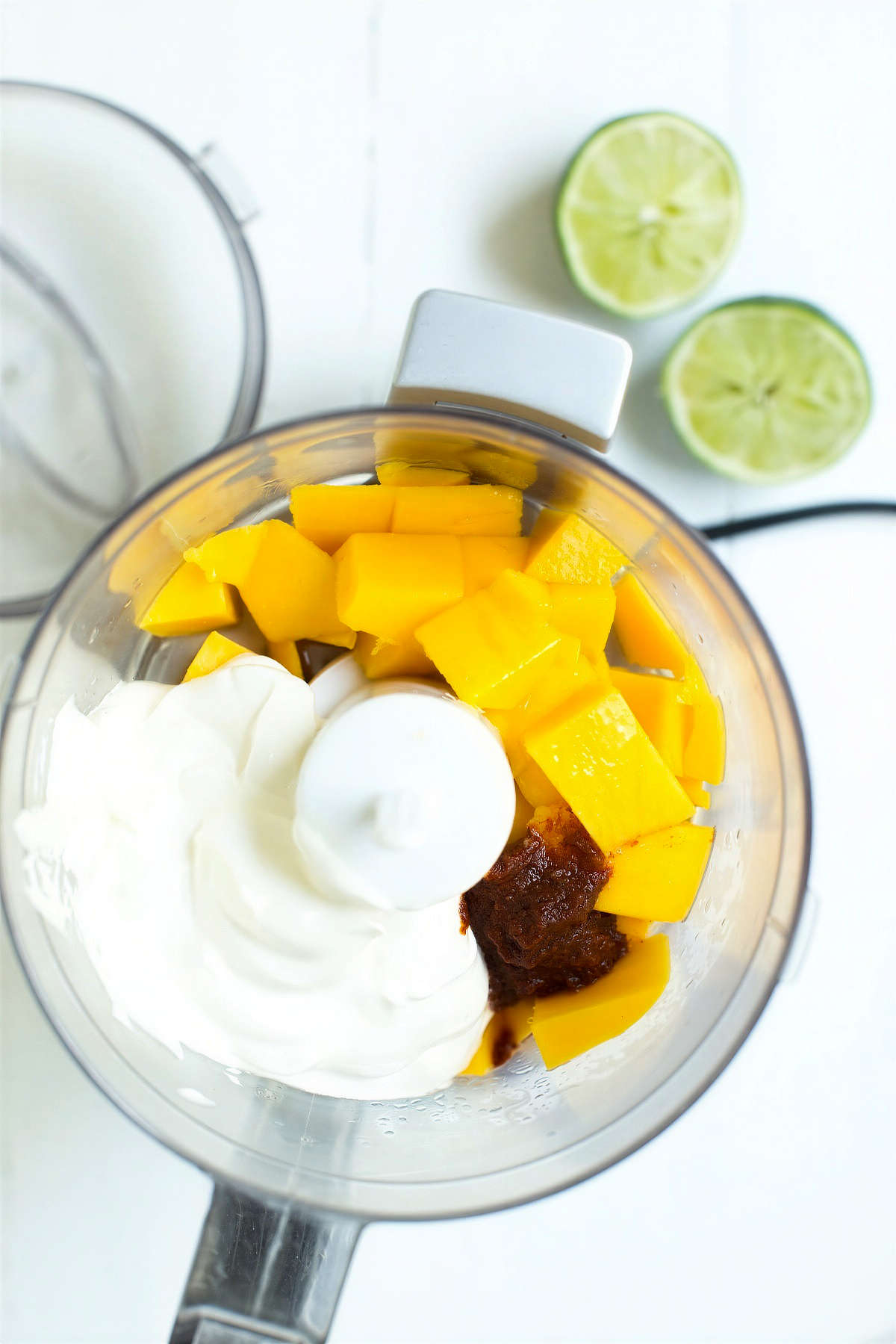 Mango chipotle sauce ingredients in a blender with mango, sour cream, and chipotle paste