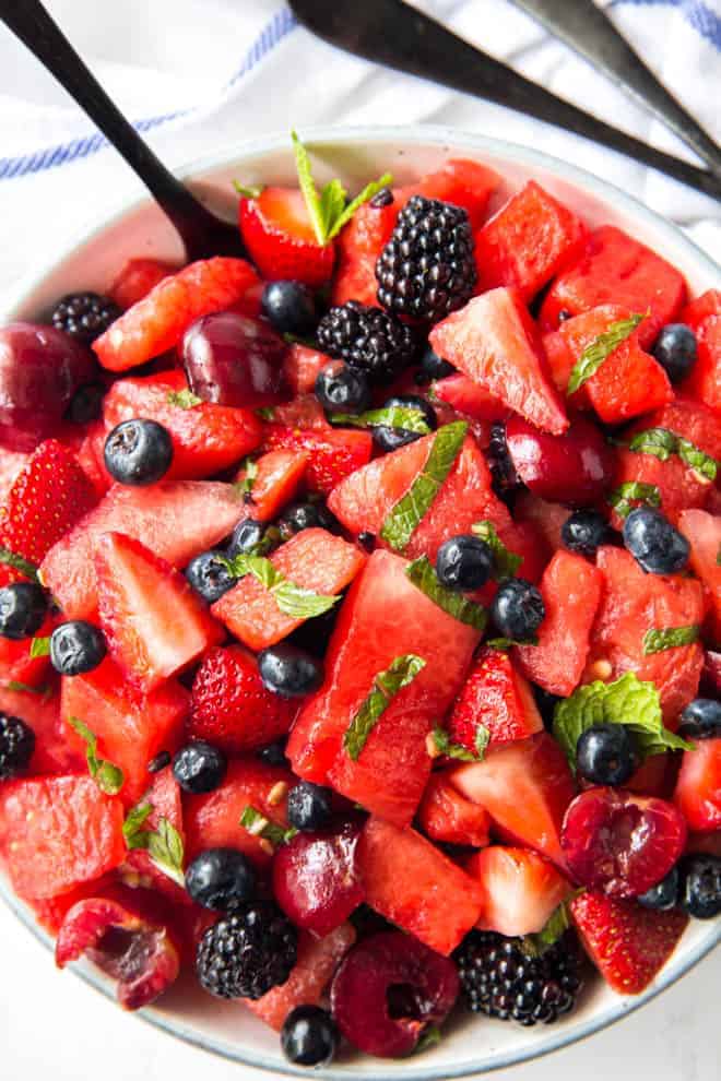 A large bowl of watermelon chunks, berries and cherries with mint.