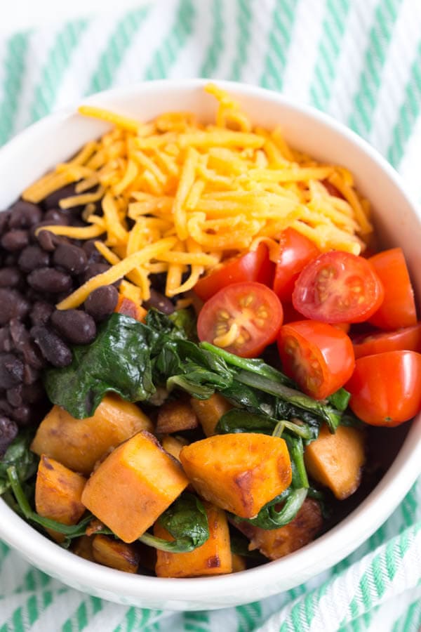 Sautéed Sweet Potato and Greens Breakfast Bowl is made with sweet potato, fresh greens, black beans, tomatoes, cheese, egg and avocado! This simple and healthy meal is perfect for any day of the week. 