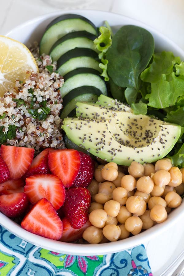 Nourish yourself with a berry green Buddha bowl packed with protein, fresh greens, vegetables, berries and topped with a creamy lemon avocado kale mint dressing!