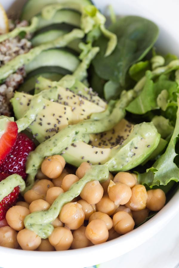 Nourish yourself with a berry green Buddha bowl packed with protein, fresh greens, vegetables, berries and topped with a creamy lemon avocado kale mint dressing!