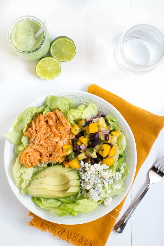 Pineapple Mango Buffalo Chicken Taco Bowls with Avocado Ranch Dressing are loaded with buffalo chicken, butter lettuce, mango pineapple and black bean salsa, blue cheese crumbles, avocado and topped with a creamy avocado ranch dressing!
