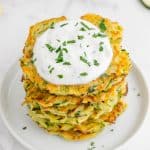a plate of zuchinni fritters with yogurt dip on top