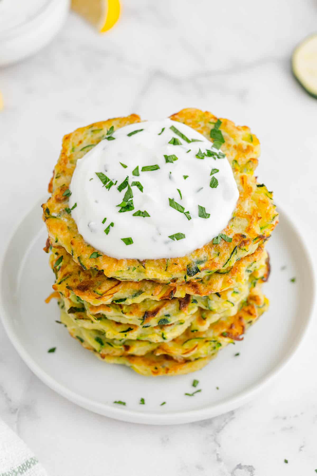 a plate of zuchinni fritters with yogurt dip on top