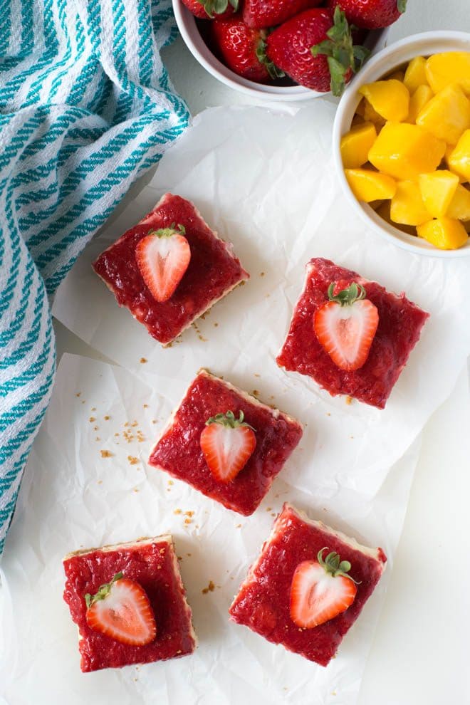 Mango Strawberry Cheesecake Bars are an irresistible treat made with ripe mango, strawberries, cream cheese, sour cream and a few other simple ingredients. They are the perfect summer dessert and combine a light and creamy mango cheesecake with strawberry topping! #mango #cheesecake #strawberry #bars #dessert #recipe #dessertrecipe