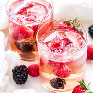 two clear glasses filled with rose sangria and fresh strawberries and blackberries
