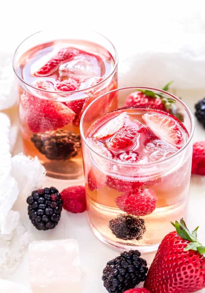 two clear glasses filled with rose sangria and fresh strawberries and blackberries