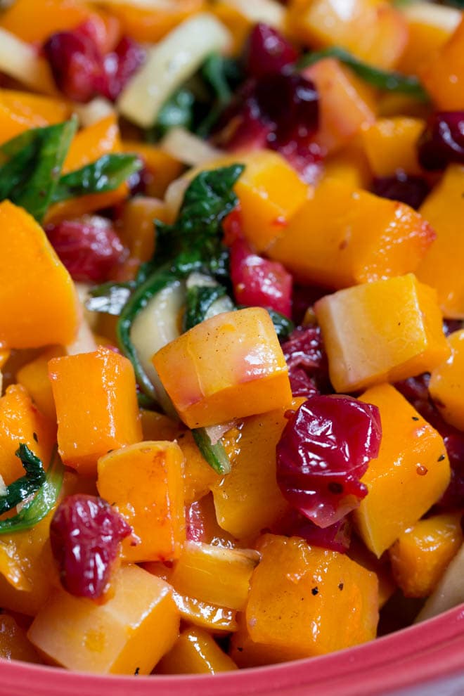 Combine a few simple ingredients together to create this Roasted Butternut Squash with Cranberries, Greens and Apples! The side dish is naturally gluten free and paleo. It's the perfect side dish for dinner or holiday parties. #roasted #butternutsquash #sidedish #cranberries #thanksgiving #healthy #paleo #glutenfree #recipe