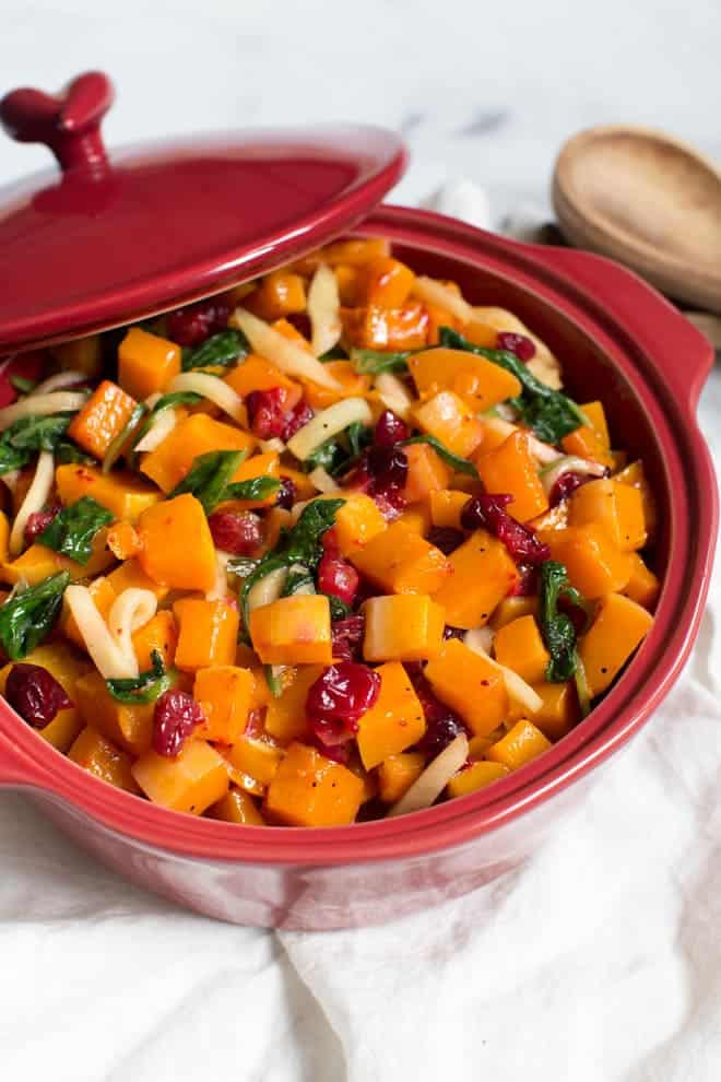 Combine a few simple ingredients together to create this Roasted Butternut Squash with Cranberries, Greens and Apples! The side dish is naturally gluten free and paleo. It's the perfect side dish for dinner or holiday parties. #roasted #butternutsquash #sidedish #cranberries #thanksgiving #healthy #paleo #glutenfree #recipe 