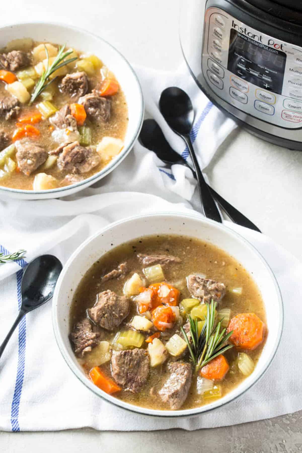 Two bowls of instant pot beef stew in front of an instant pot.