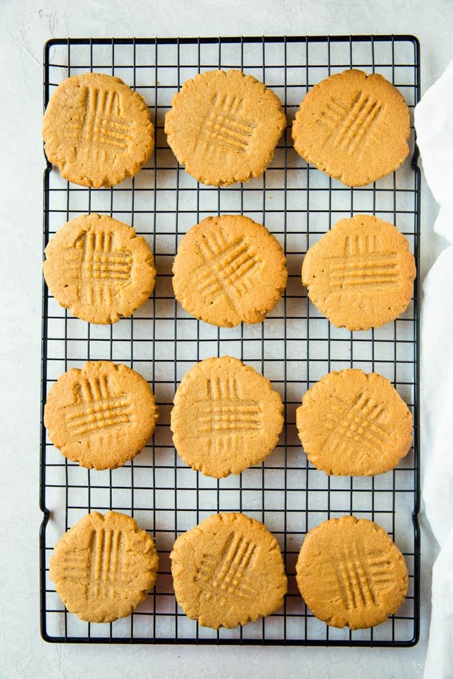 one dozen peanut butter cookies sitting on a cooling rack on a white countertop