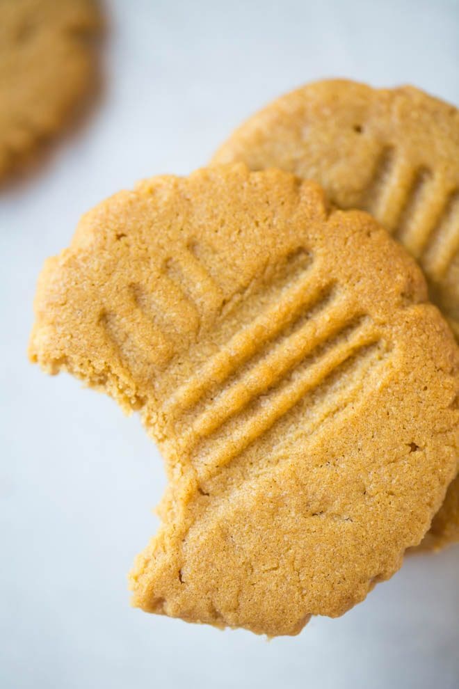 a peanut butter cookie with a bite taken out of it sitting on top of other cookies