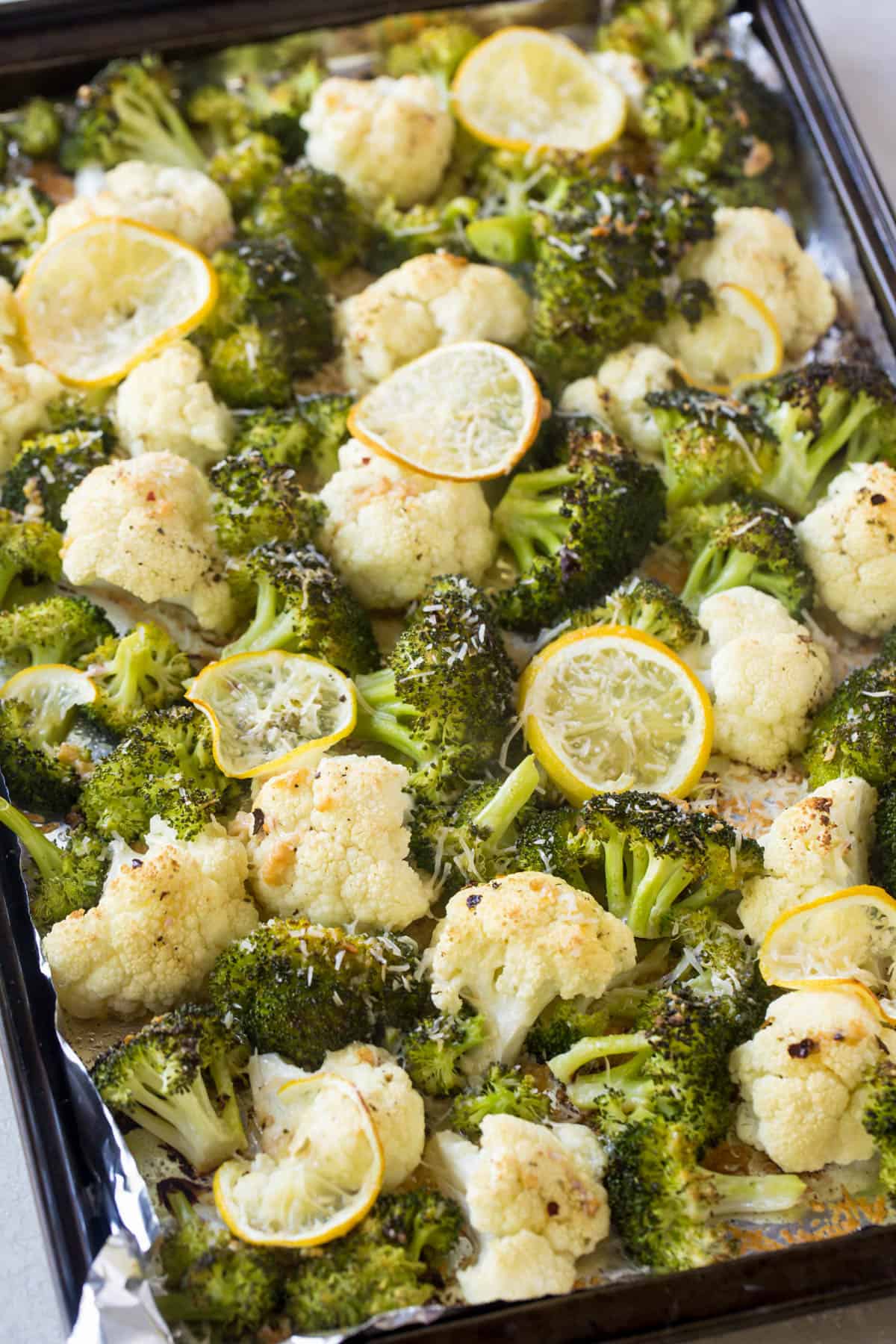 Crispy roasted cauliflower and broccoli on a sheet pan with grated cheese sprinkled on top.