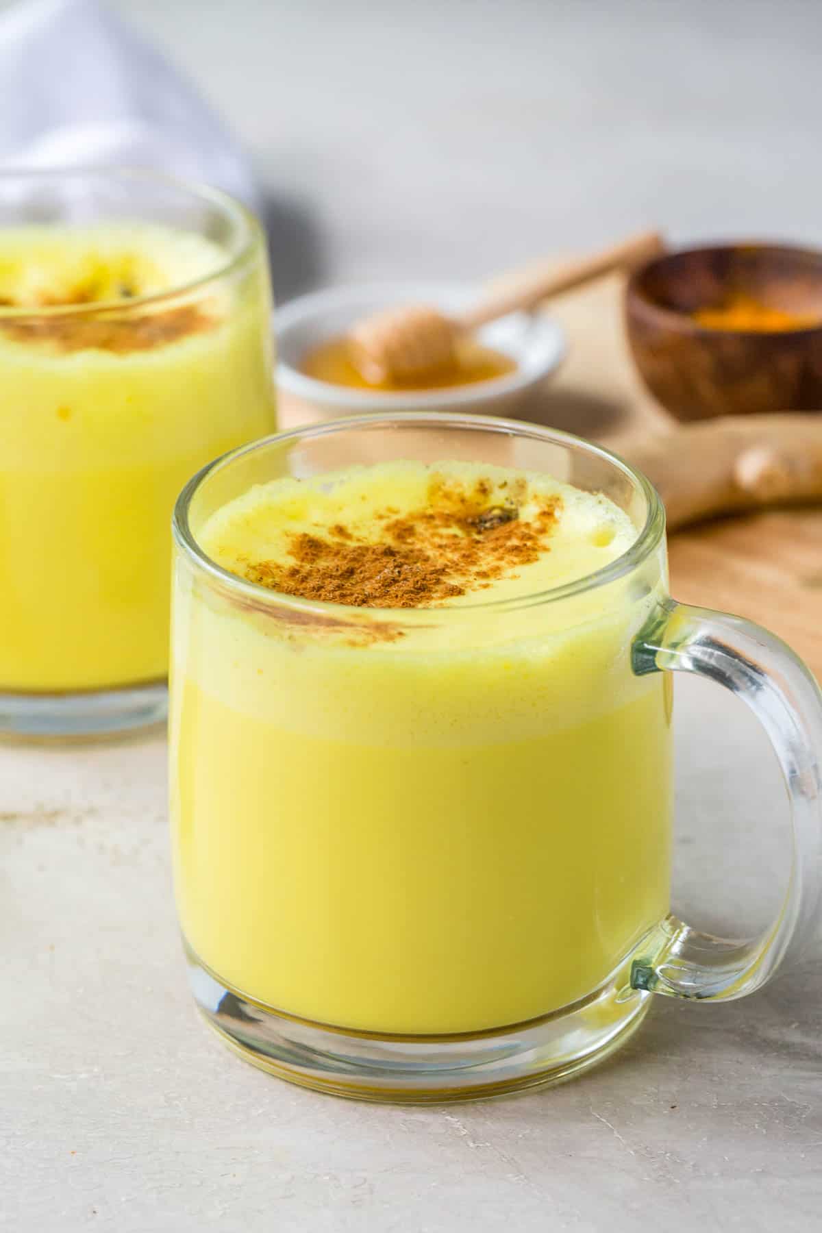 golden milk in a glass mug with cinnamon sprinkled on top
