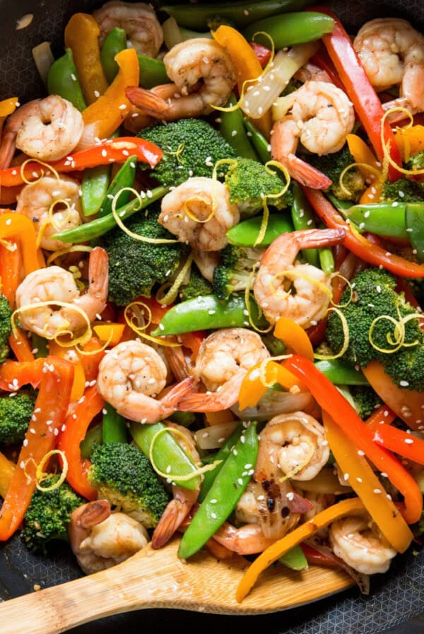 Overhead shot of stir fry shrimp, broccoli, peppers, and snap peas in a skillet.