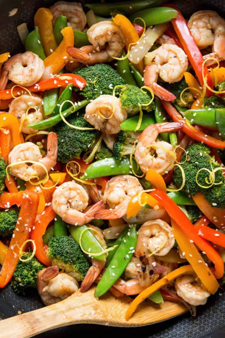 Overhead shot of stir fry shrimp, broccoli, peppers, and snap peas in a skillet.