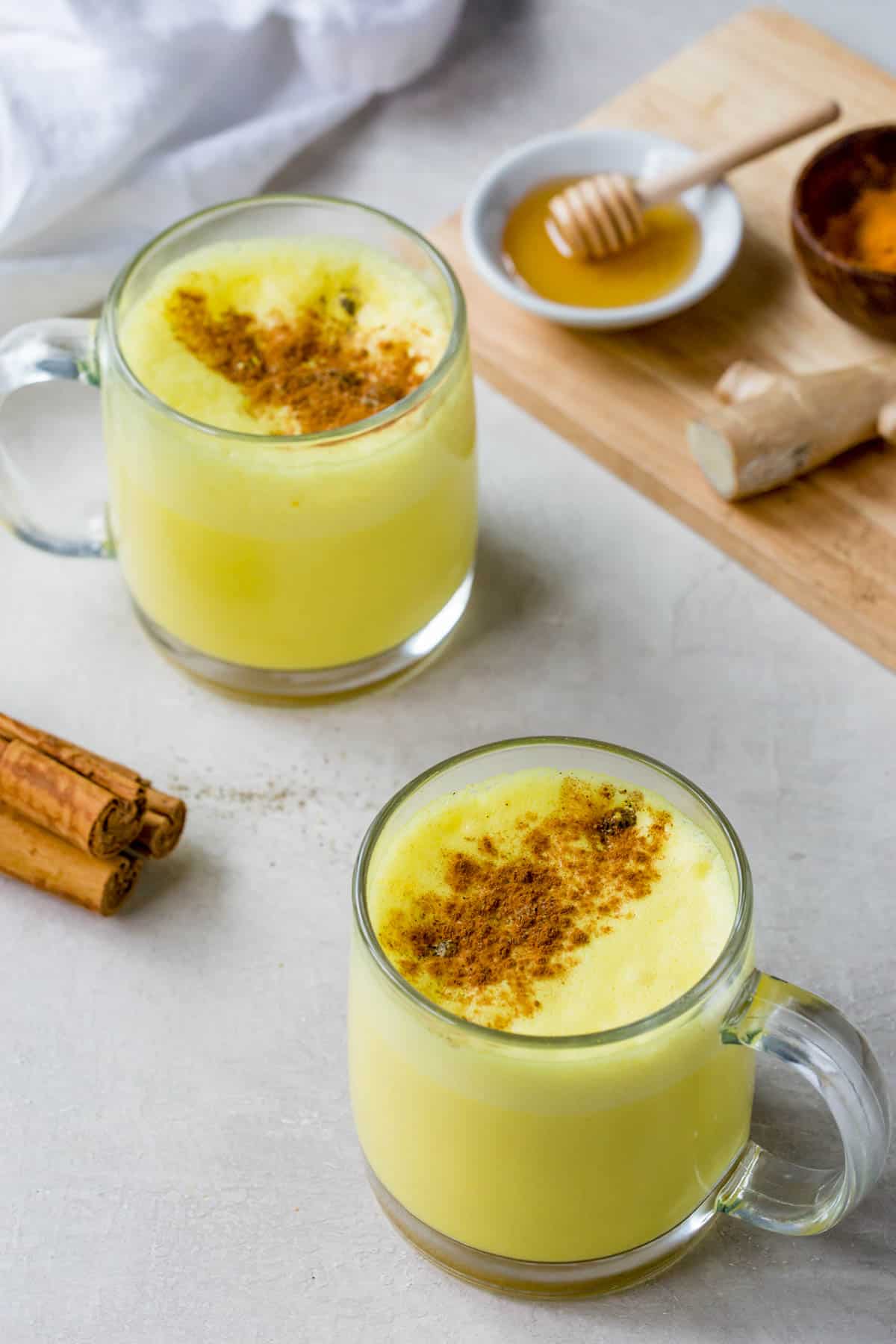 two cups of turmeric latte sitting on a tabletop