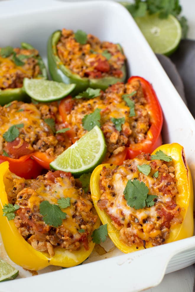 Six turkey quinoa stuffed peppers in a white rectangle baking dish.