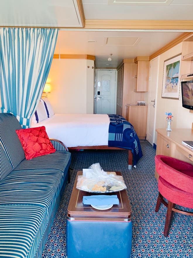 cruise ship cabin room with bed, couch and chair.