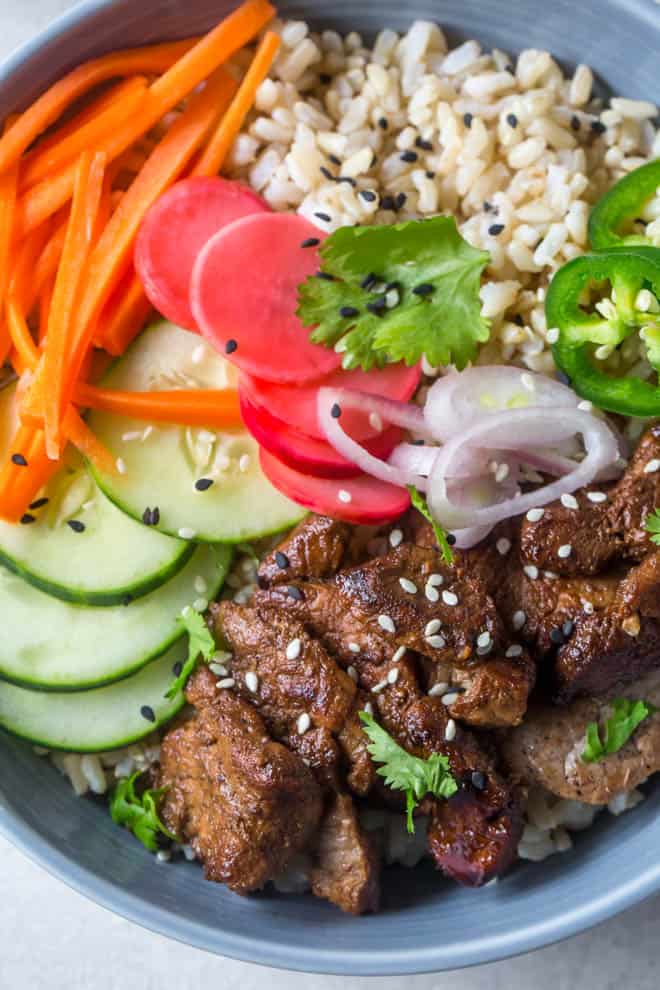 Rice bowl with pork tenderloin, pickled carrots, cucumbers, onions and rice.