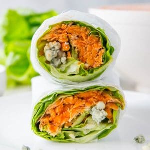 Two buffalo lettuce chicken wraps stacked on top of each other on a white background.