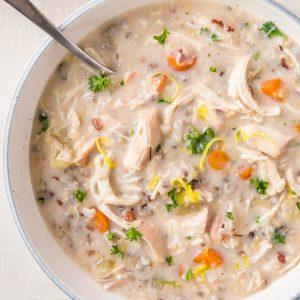A large bowl of chicken and wild rice soup sits on a white table.
