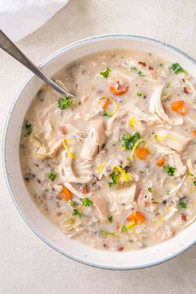 A large bowl of chicken and wild rice soup sits on a white table. 