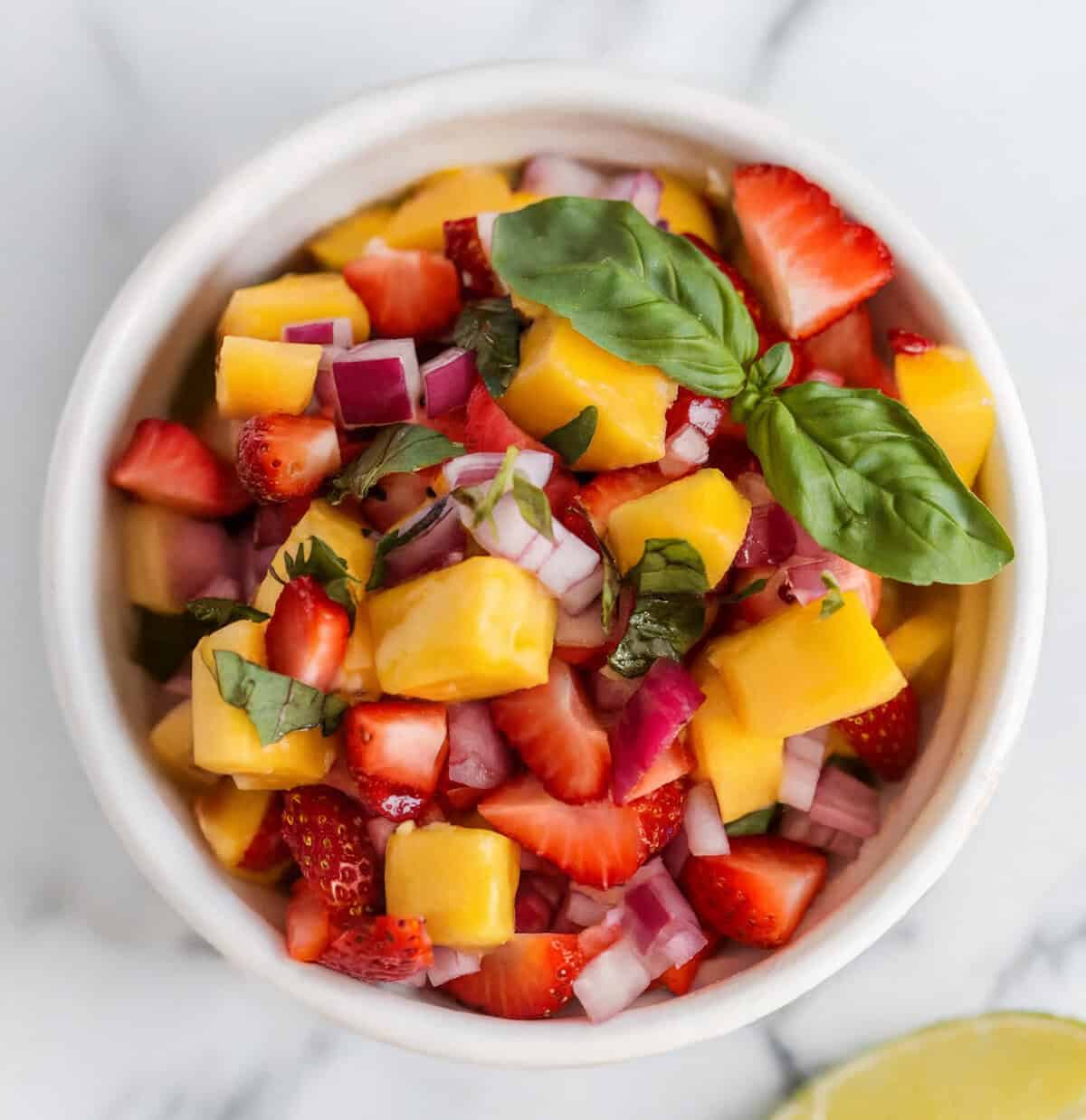 Overhead view of a small bowl of strawberry mango salsa
