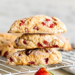 A pile of three strawberry scones sitting on a cooling rack.