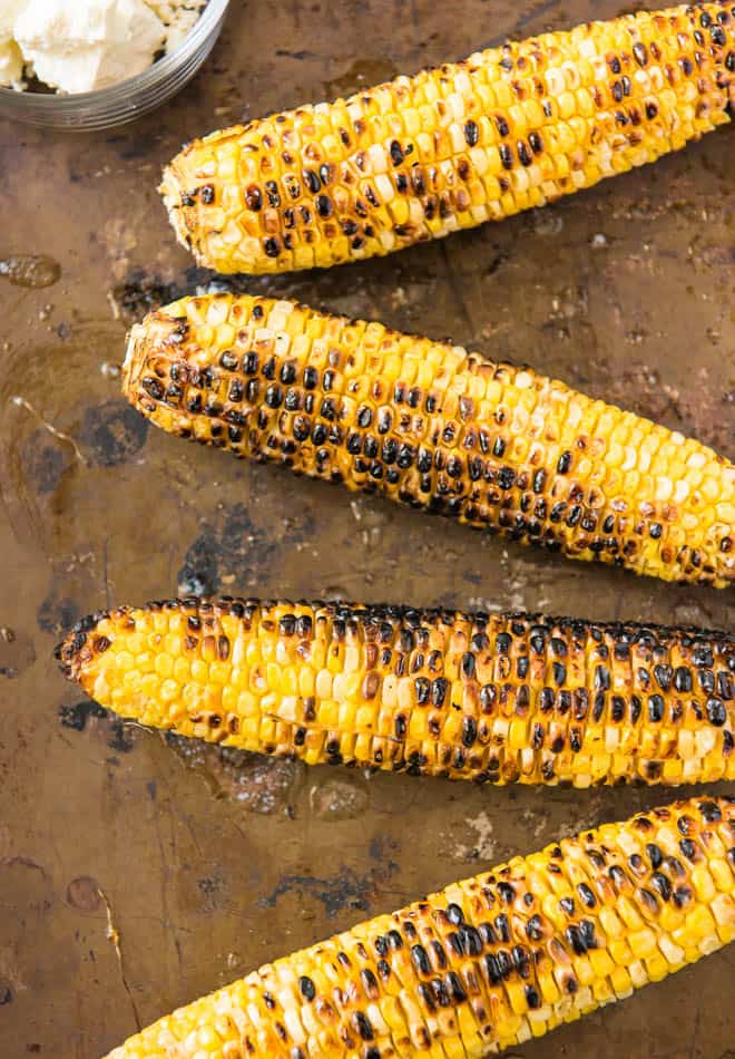 Four pieces of grilled corn.