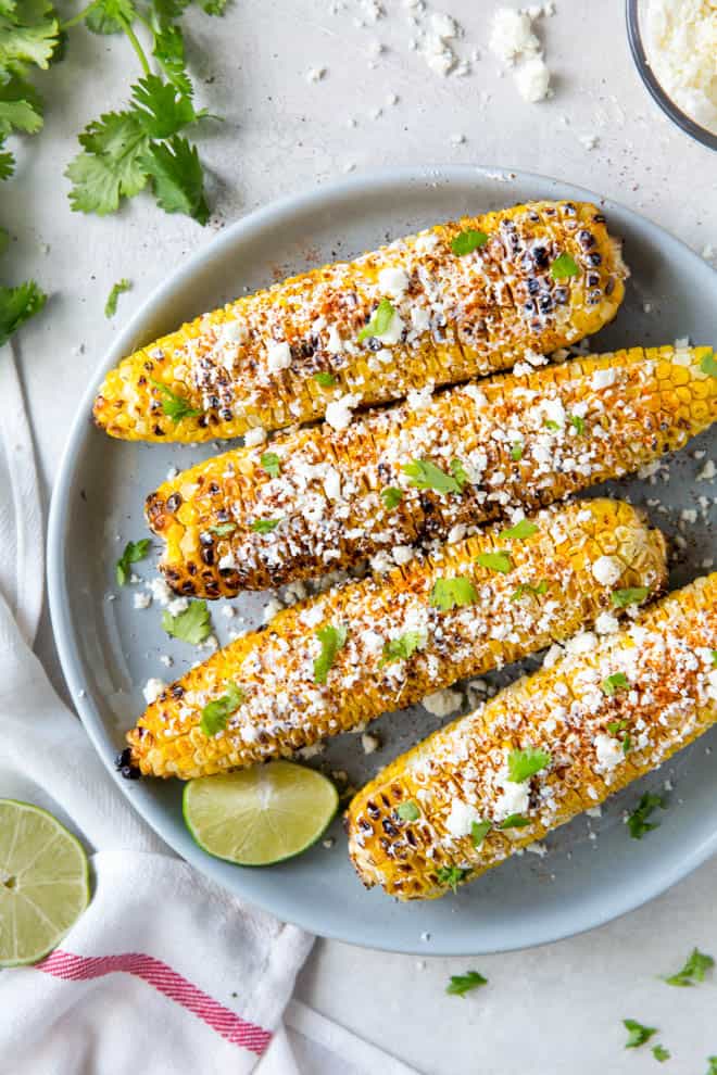 Four pieces of elote corn sitting on a blue plate.